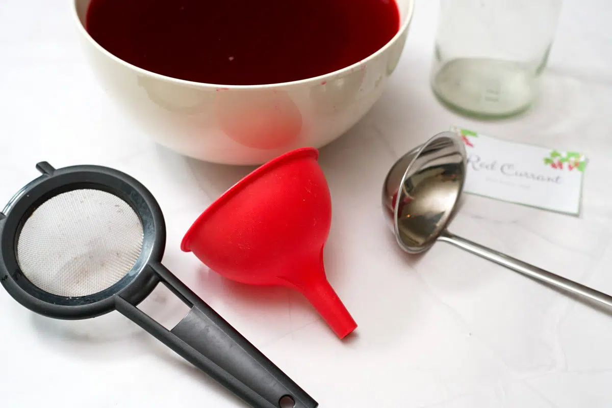 Strainer, ladle, funnel and bottle on table. 