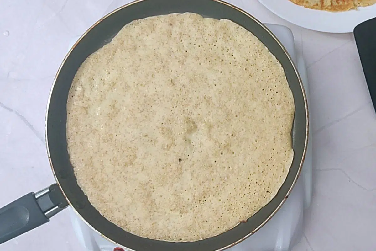 Thin crepe pancake on non stick large pan before turning. 