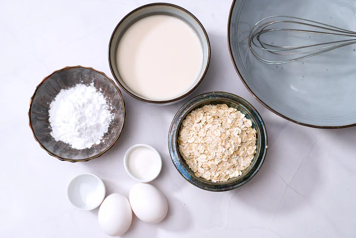 Milk, rolled oats, starch, sugar and salt in cups and eggs on the surface. 