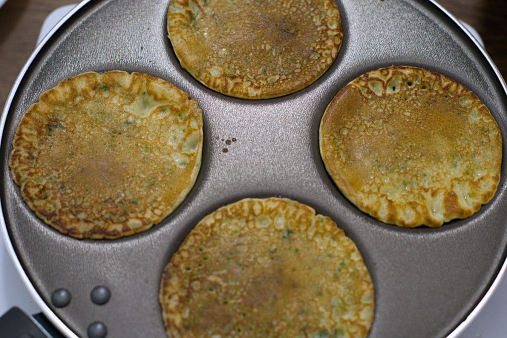 A teflon pan with four small holes for pancakes. 