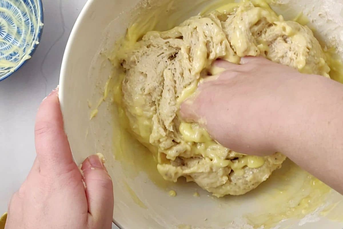 butter added to dough and hand kneading it.