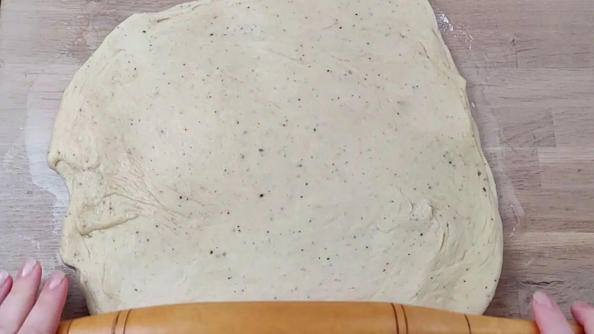 a rolling pin rolling out thin sqare dough.