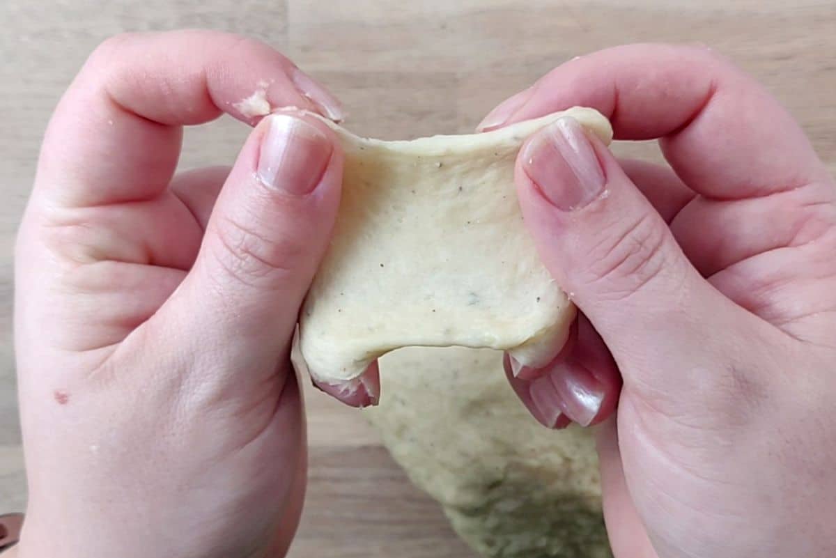 a piece of dough streched between fingers. 