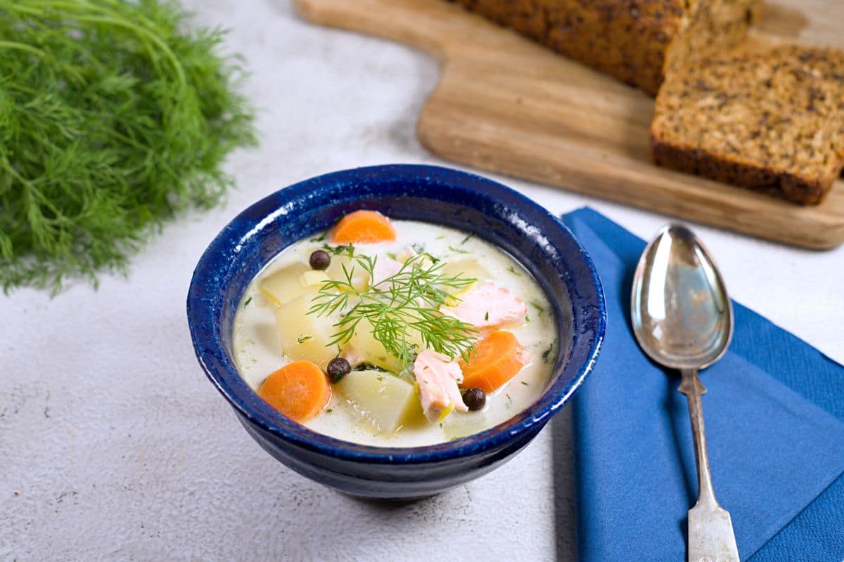 creamy salmon soup in a blue bowl served with rye bread. 
