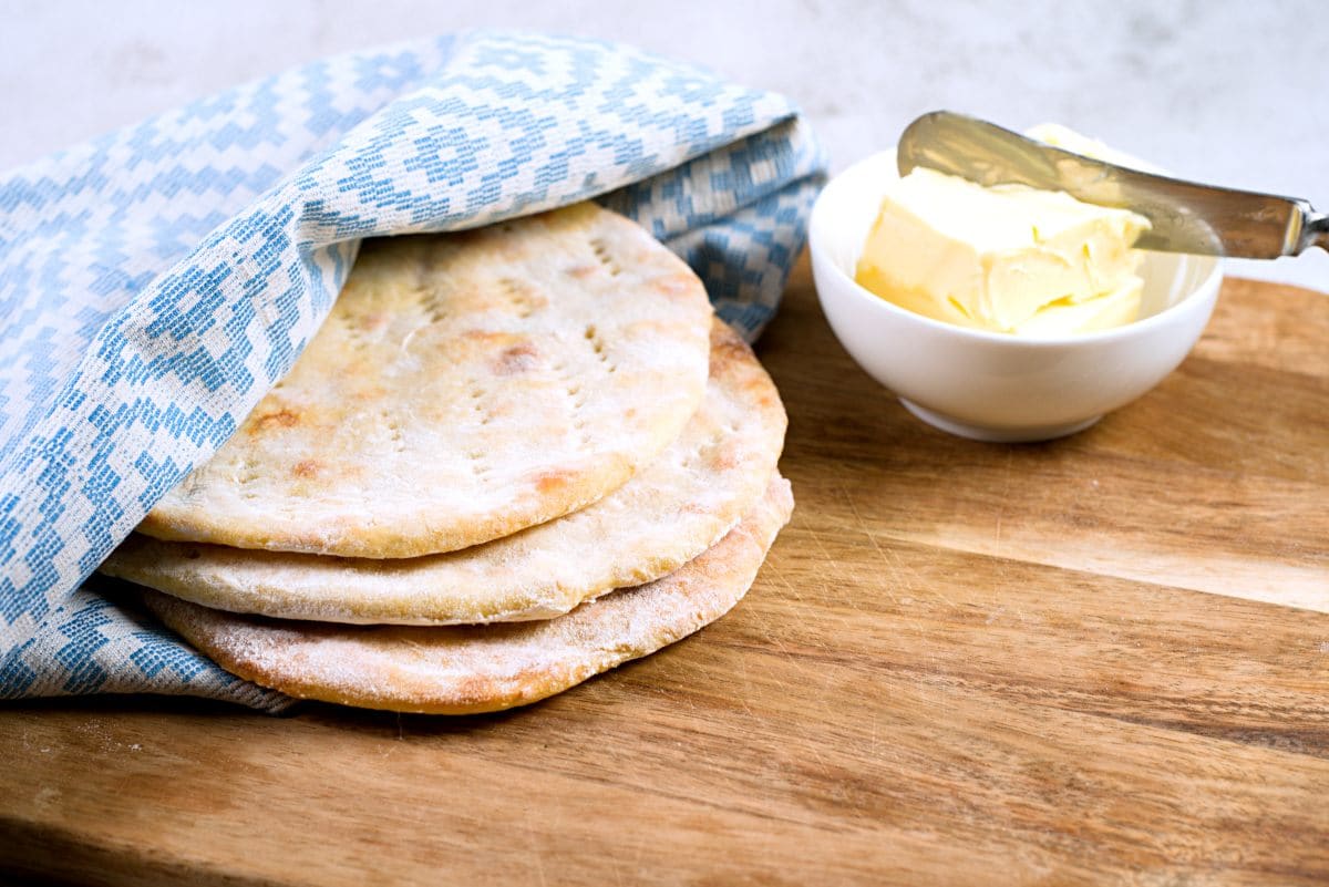 flatbreads on pile with blue napkin and butter. 