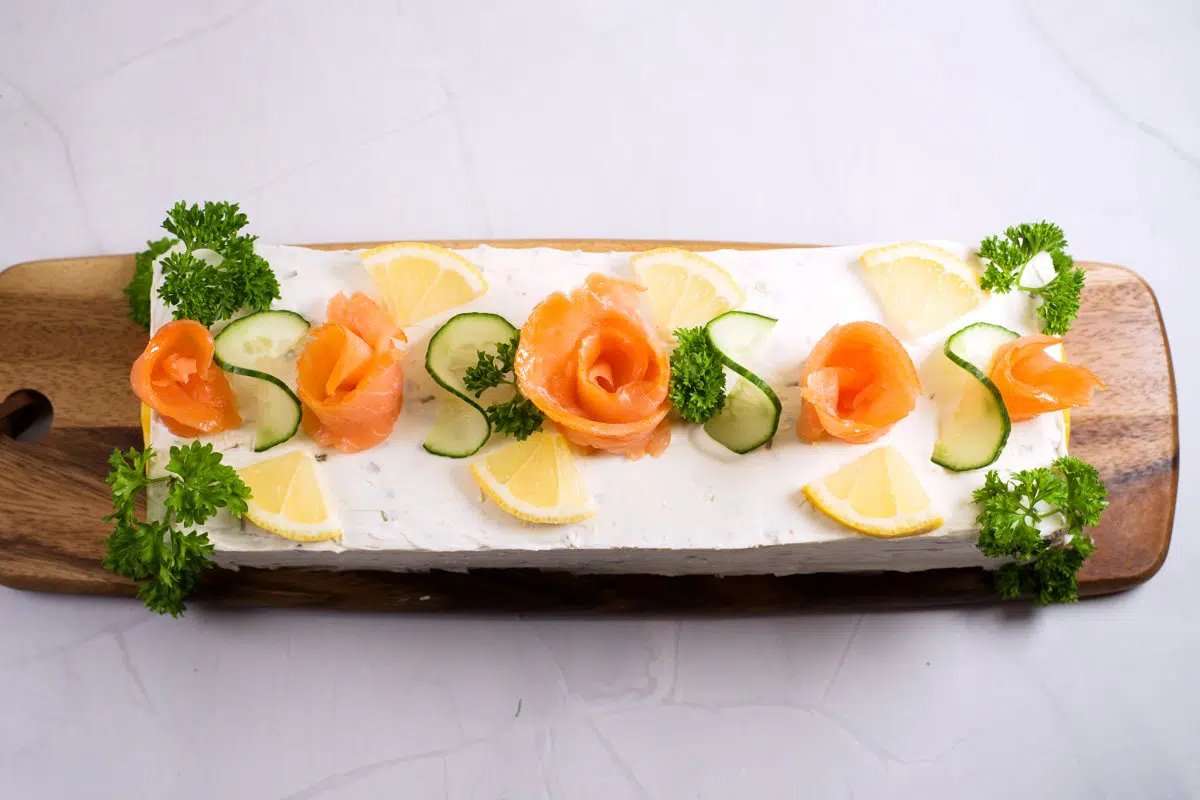 sandwich cake from above with salmon roses, lemon wedges, cucumber and parsley. 