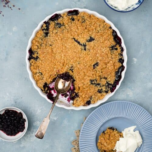 Blueberry pie from above. crumbly top with oats. Cream on the side.
