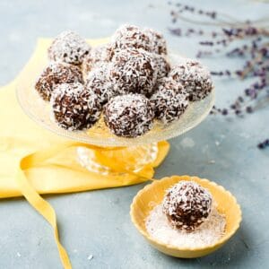 oat-balls with coconut on top on a cake plate with yellow napkin.