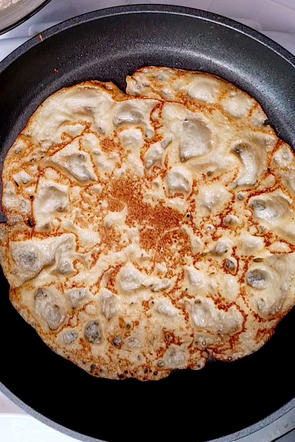 Flipped pancake with lace pattern on pan. 