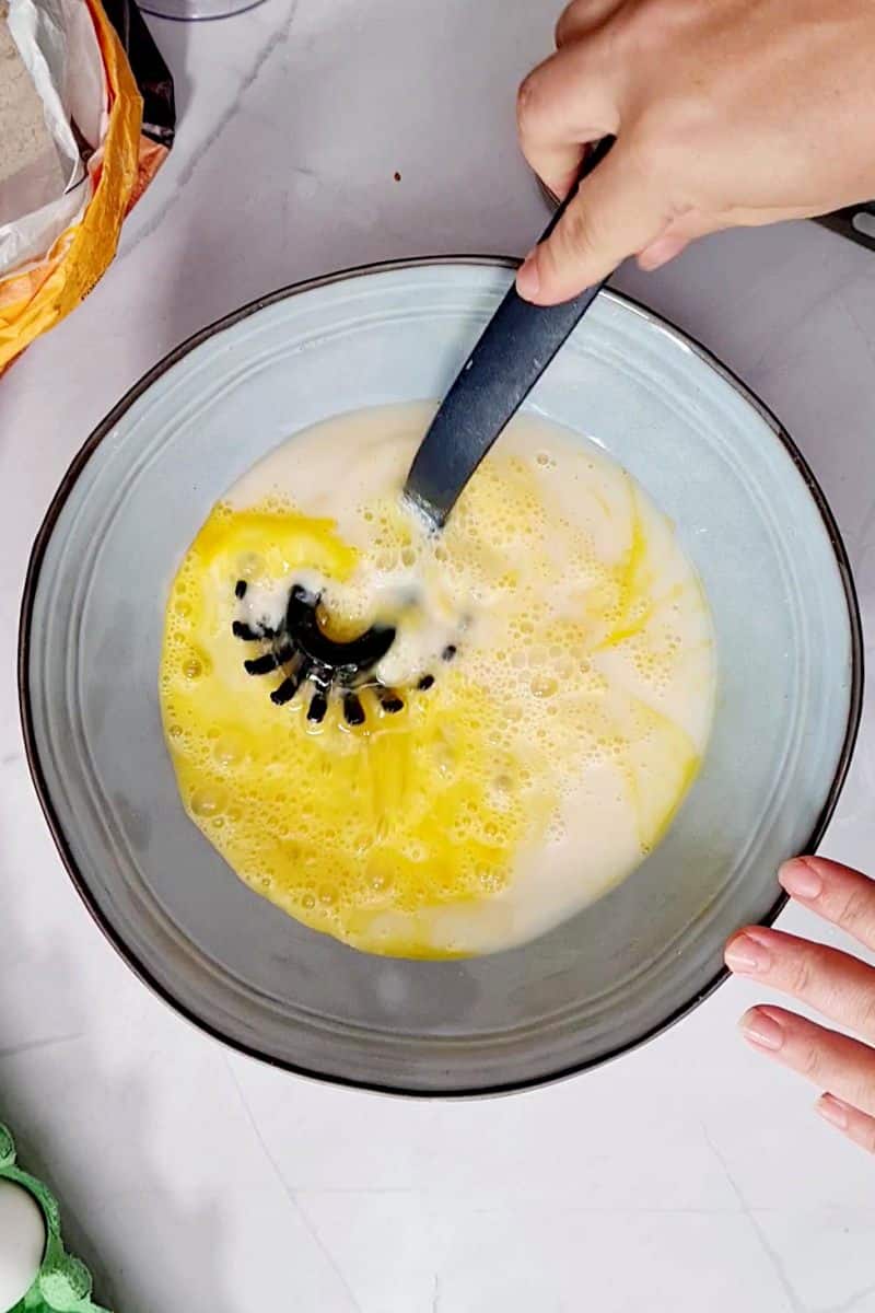 Milk and eggs being mixed in bowl. 