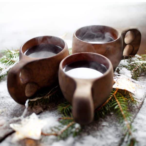 three wooden mugs, Finnish kuksa outside in snow with steaming red drink. . 