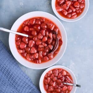 three white bowls with strawberry soup