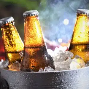 three beer bottles cooling and grill in background.