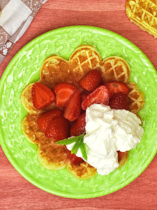 a waffle with whipped cream and fresh strawberries. 
