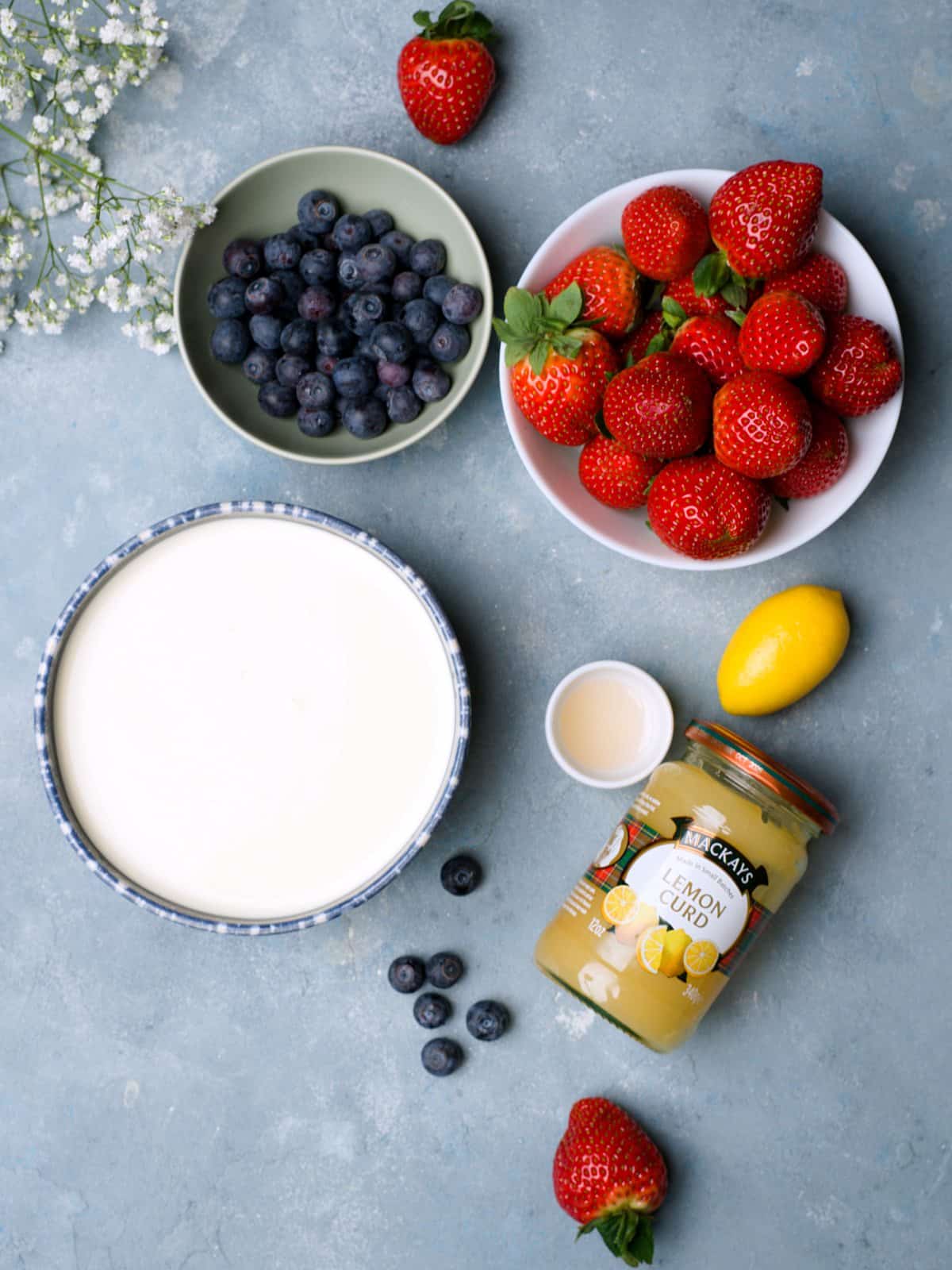 lemon curd, heavy cream, fresh strawberries on blue surface. 