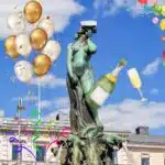 The Havis Amanda statue with a student cap and some balloons and sparkling wine in background.