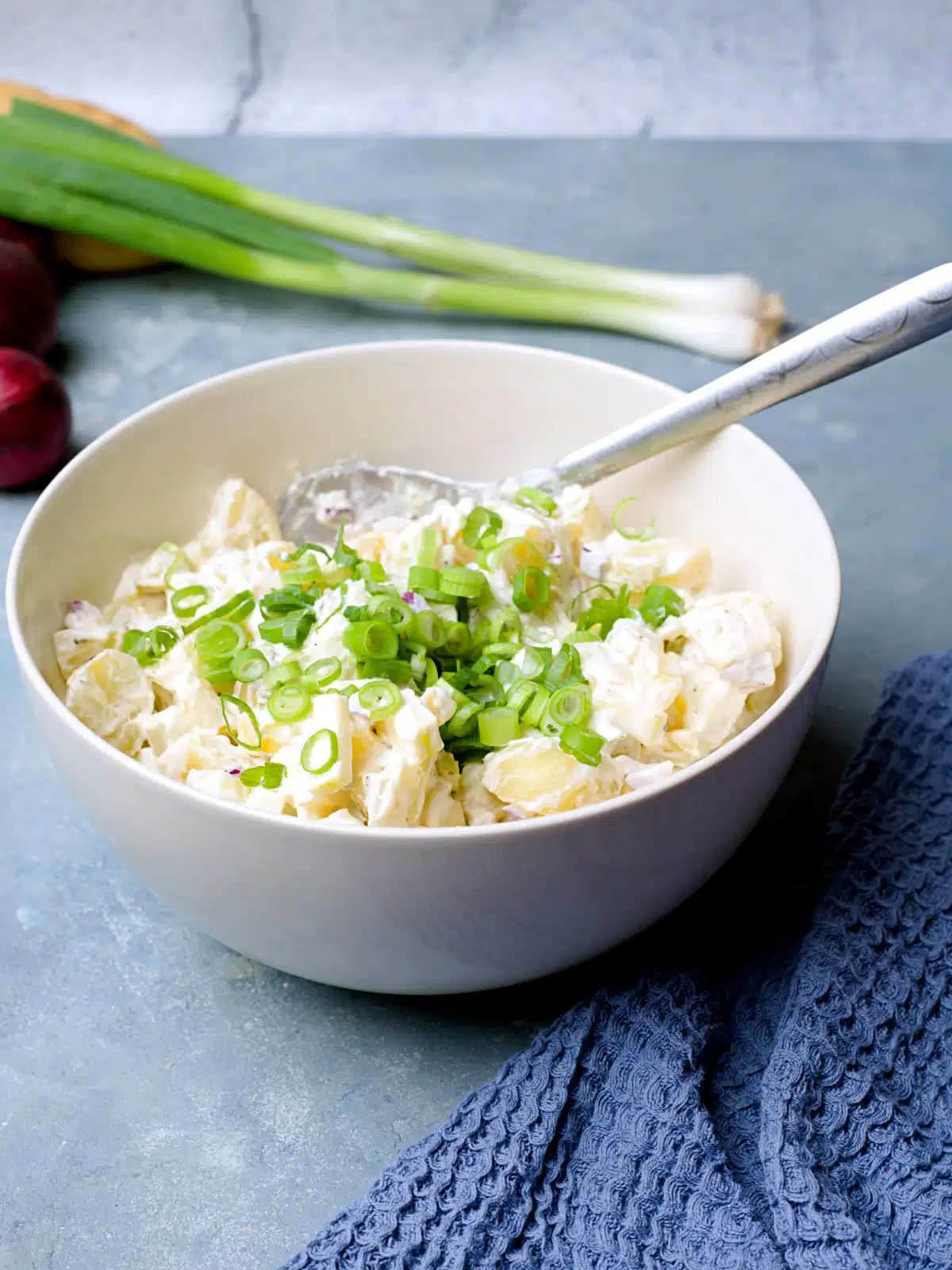 potato salad in white bowl with spring onion. 