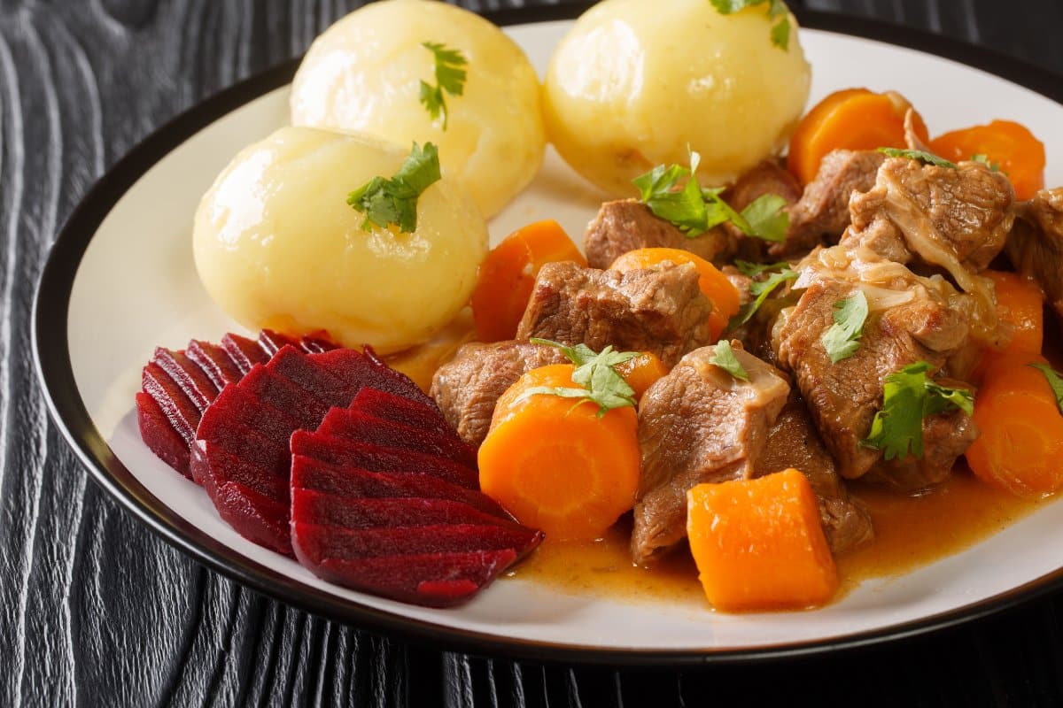 Beef stewwith carrots served with boiled potatoes and pickled beets. 