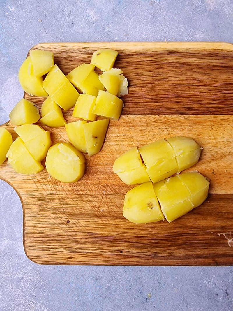 potatoes as cubes on chopping board. 