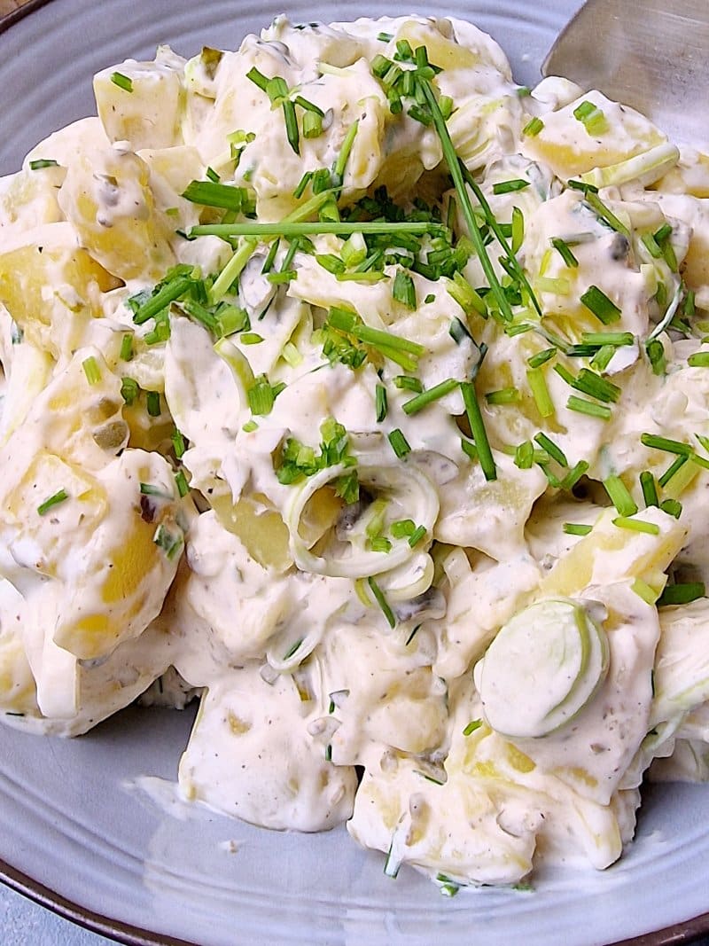 closup on potato salad in serving bowl with chopped chives on top. 