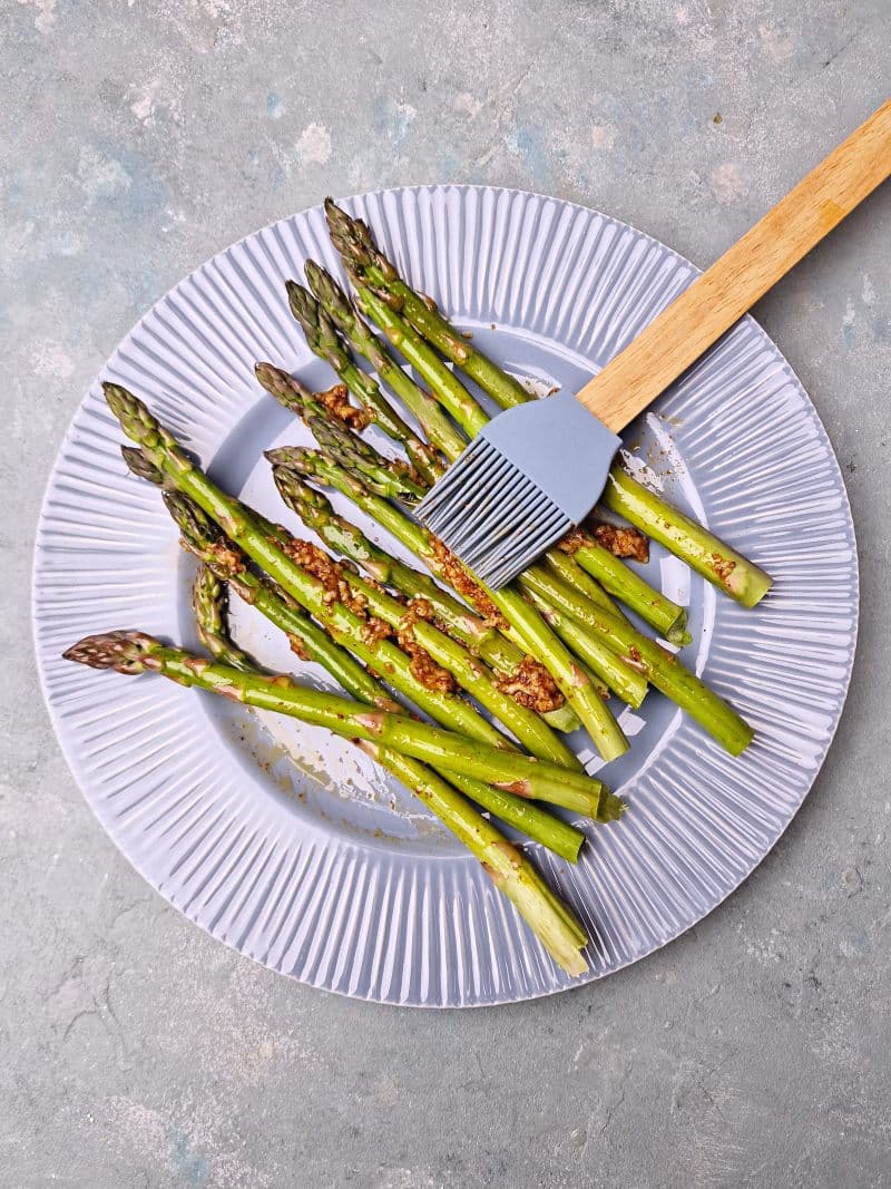 Silicone brush on asparagus spreading the oil. 