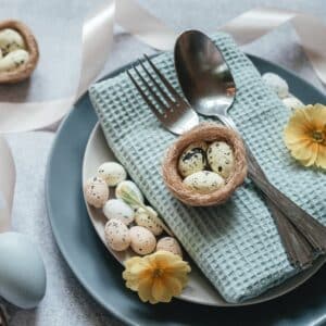 A blue plate with blue napkin and some easter eggs on table.