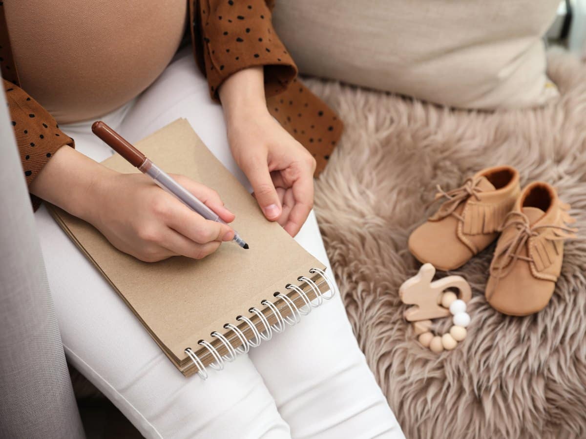 A pregnant woman with a notebook in hands.