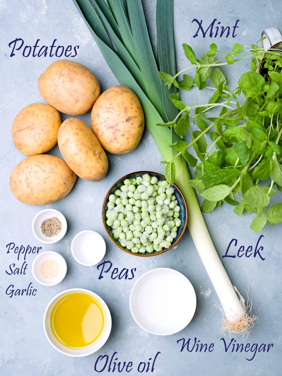 Ingredients for potato salad with peas and leek on blue surface. 