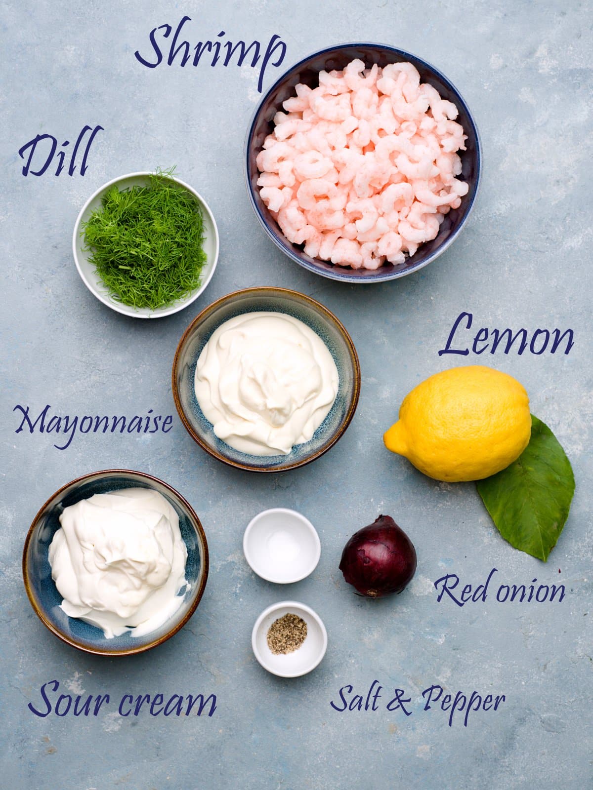 ingredients in bowls, blue background, shrimp, chopped dill, lemon, mayonnaise, sour cream, red onion, salt and pepper. 