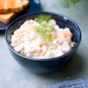 swedish shrimp salad in blue bowl with some dill as decoration.