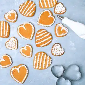 An icing piping bag and decorater heart shaped gingerbreads.