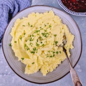 Mashed potatoes in a serving bowl decorated with parsley.