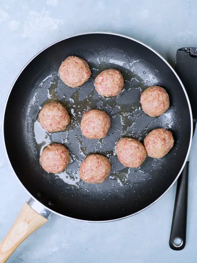 Raw meatballs spaced out on the pan.