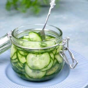 Thinly slices cucumber slices in a glass jar with liquid and dill.