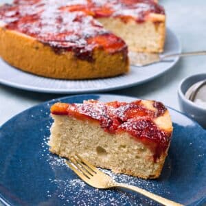 Closeup on a coffee sponge cake with plum topping and powdered sugar.