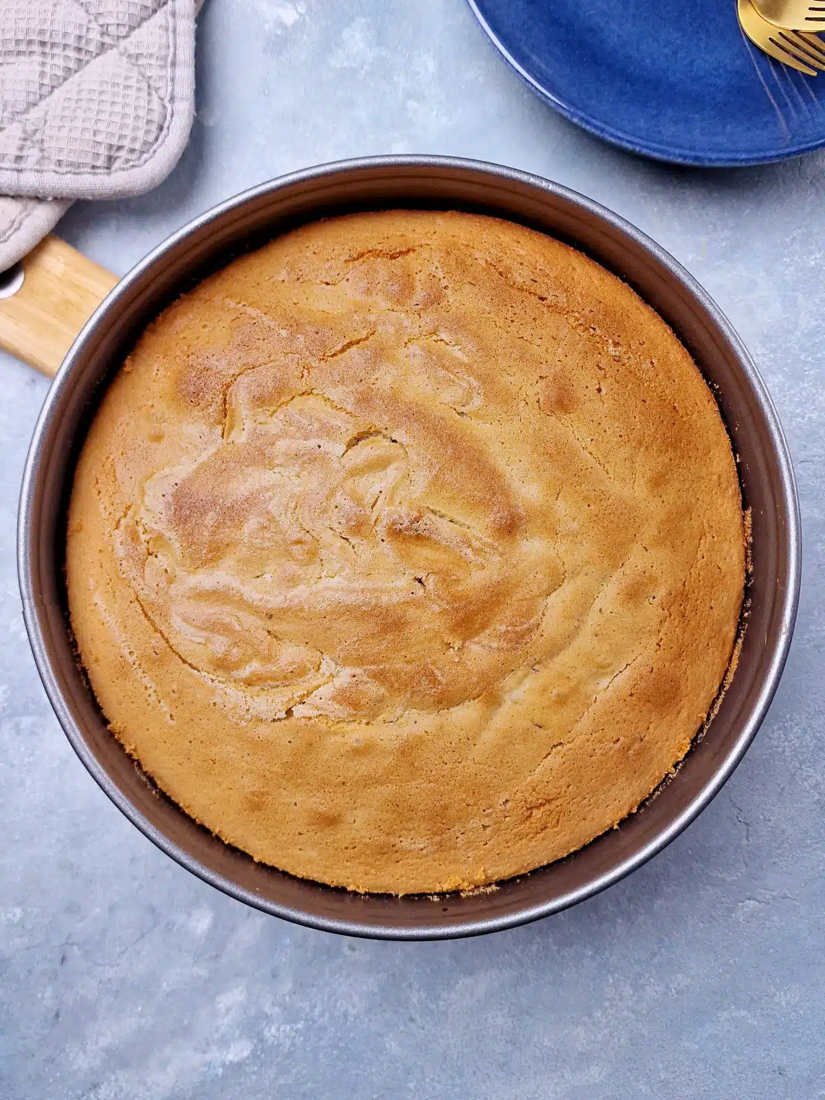 Ready baked cake in springform pan with brown color on top. 