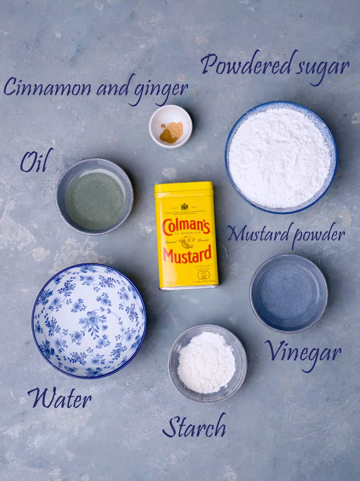 Labeled ingredients for mustard making on blue surface.