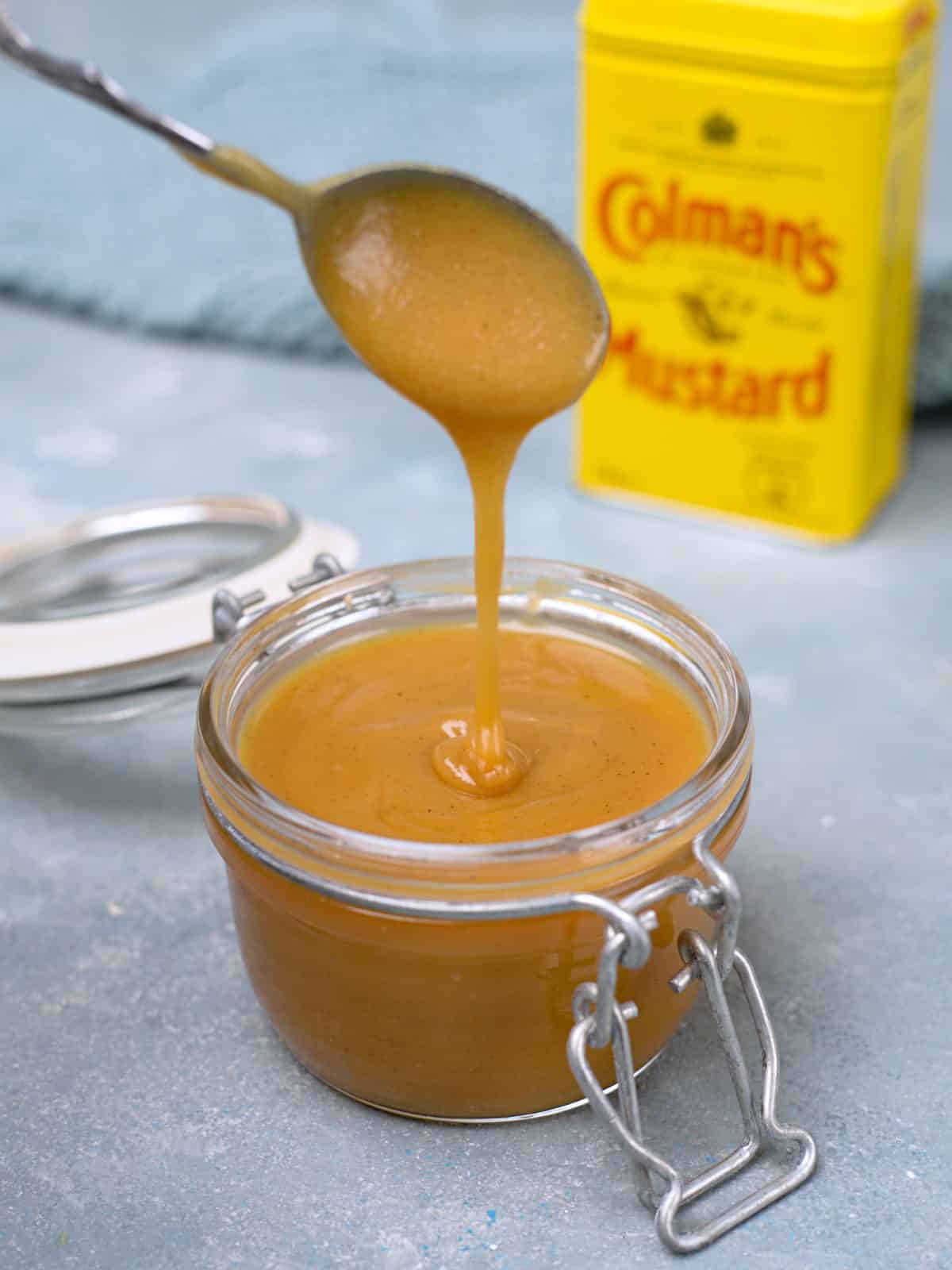 Yellow mustard powder packet and readymade mustard shown consistency by dripping it with spoon. 