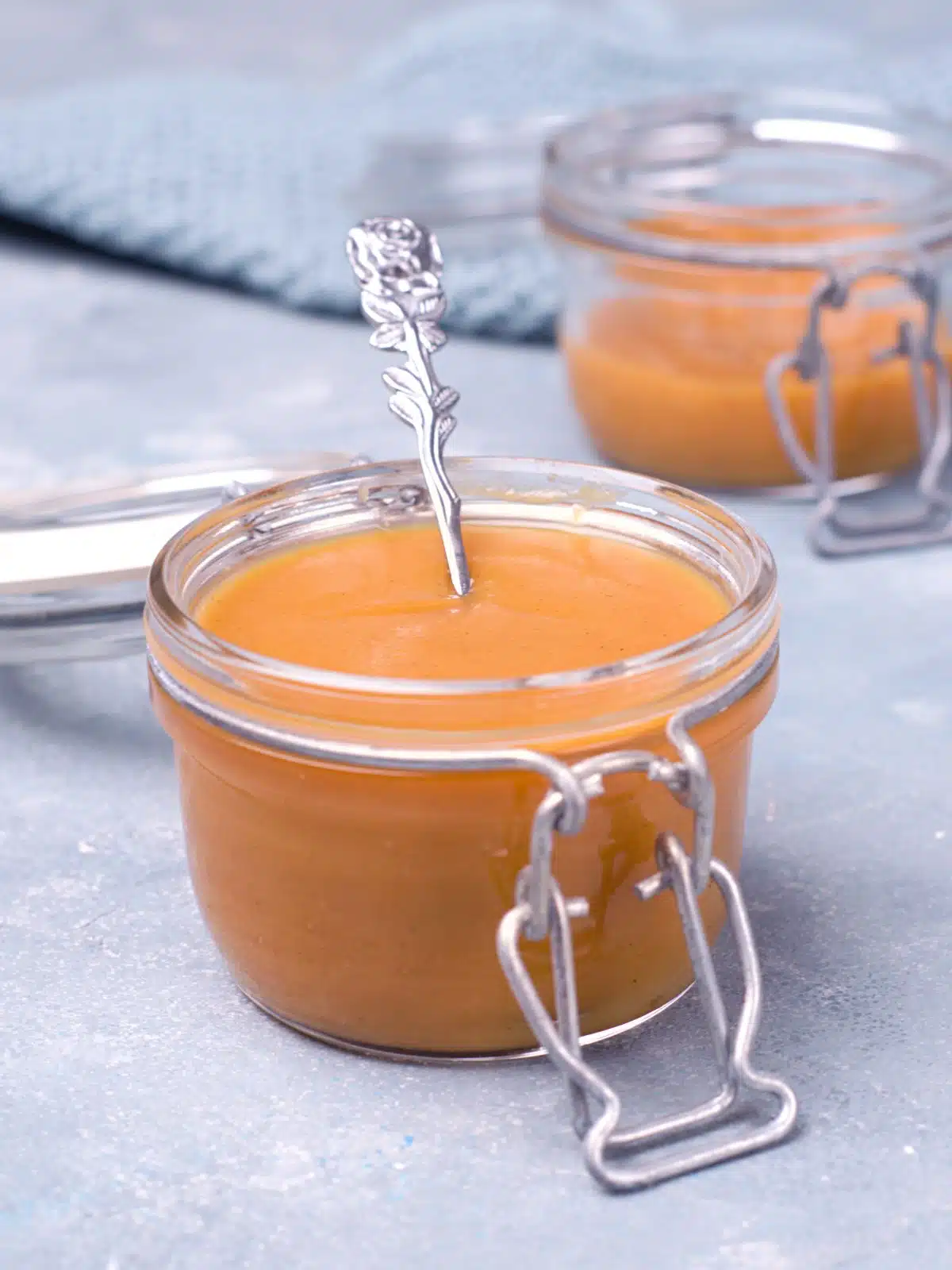 Closeup on thick mustard in glass jar with spoon.