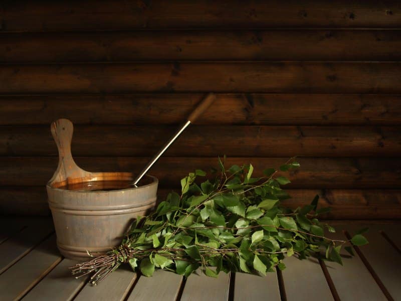 Finnish sauna with wooden kiulu, a water bucket and a vihta; tied birch branches. 