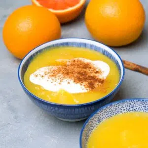 orange dessert in blue bowl with white vanilla custard